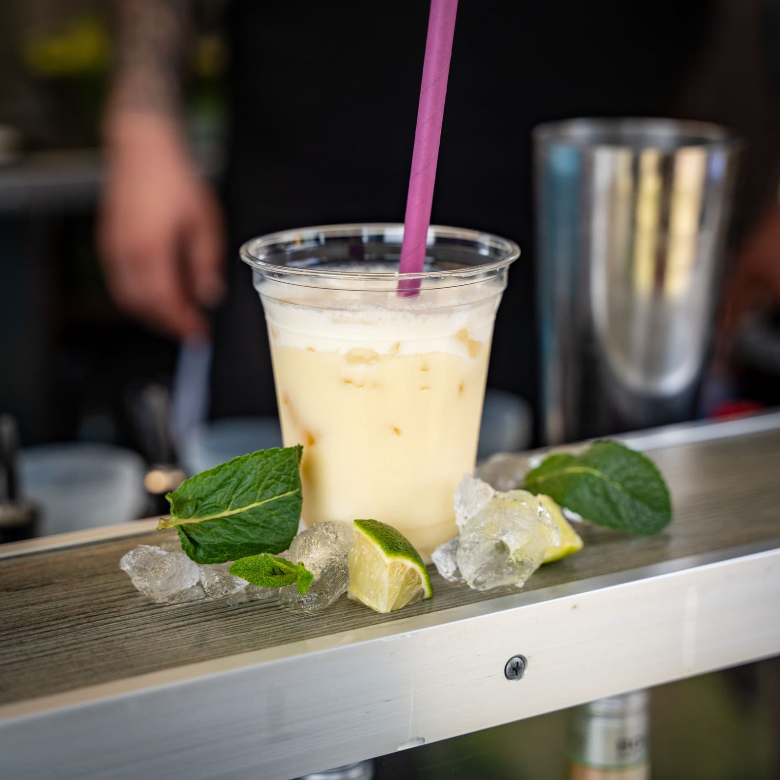 Cremig-gelber Cocktail mit Limettenspalten auf dem Tresen