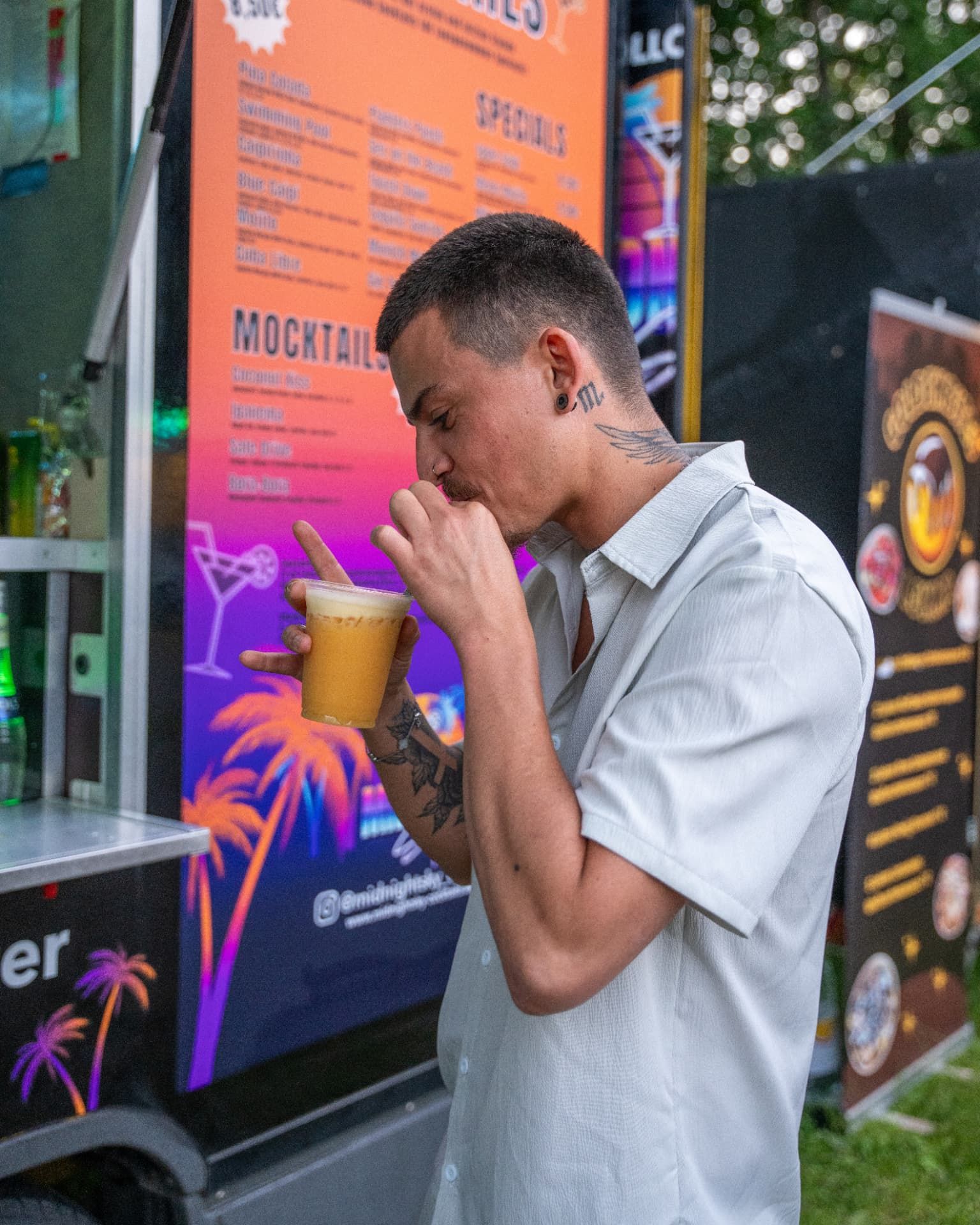 Gast trinkt einen gelben Cocktail neben der Menütafel des Trucks