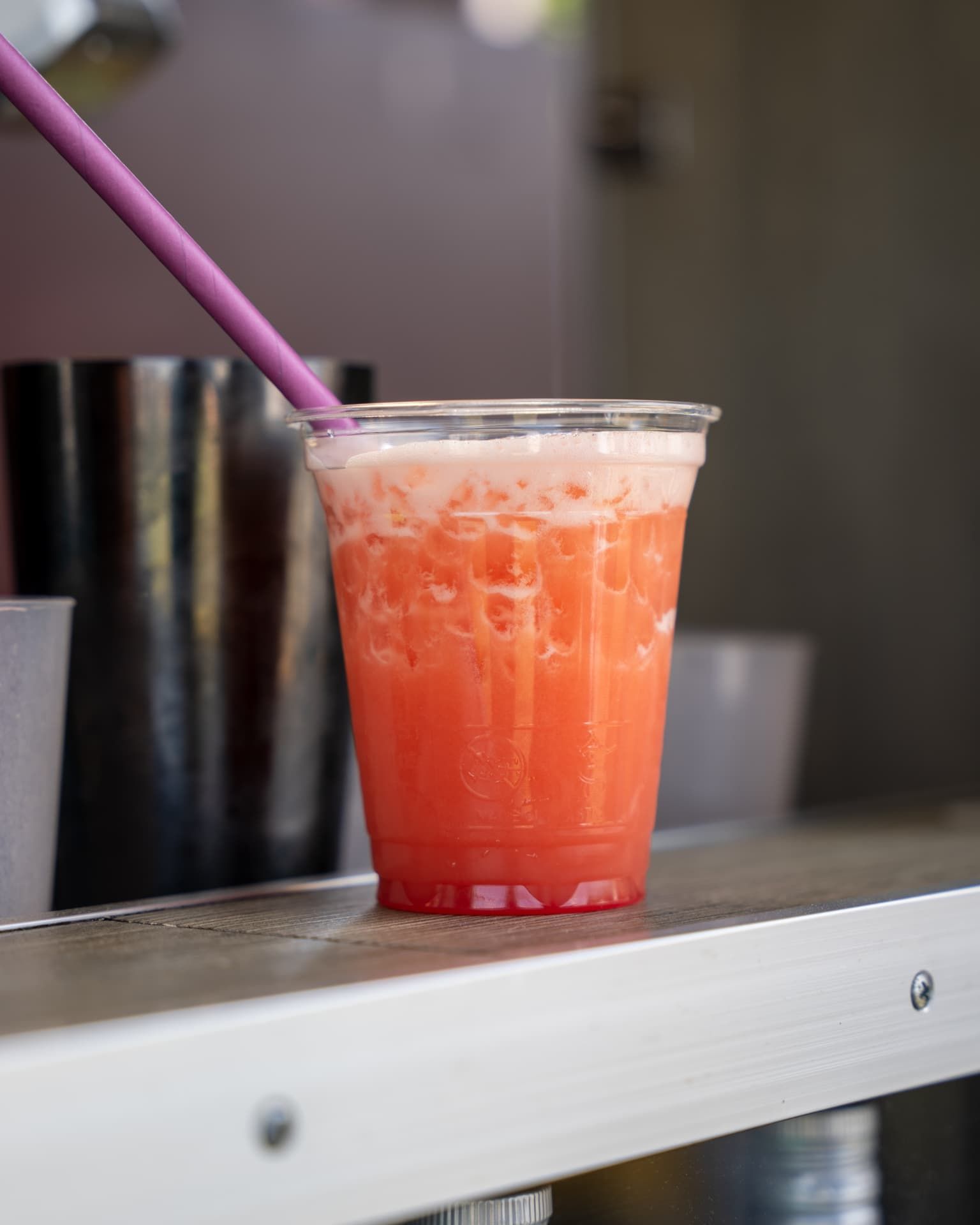 Schaumiger Cocktail in Pink-Orange mit Trinkhalm