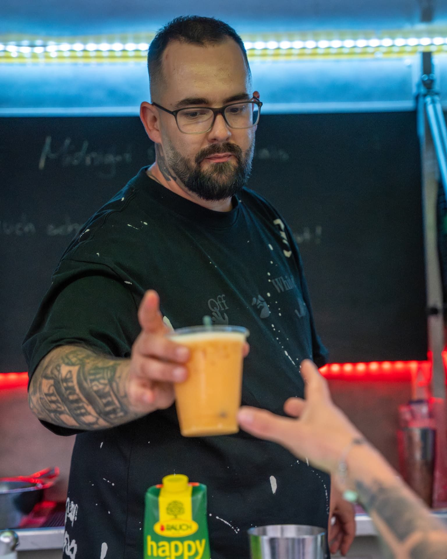 Barkeeper übergibt einen orangefarbenen Cocktail an einen Gast