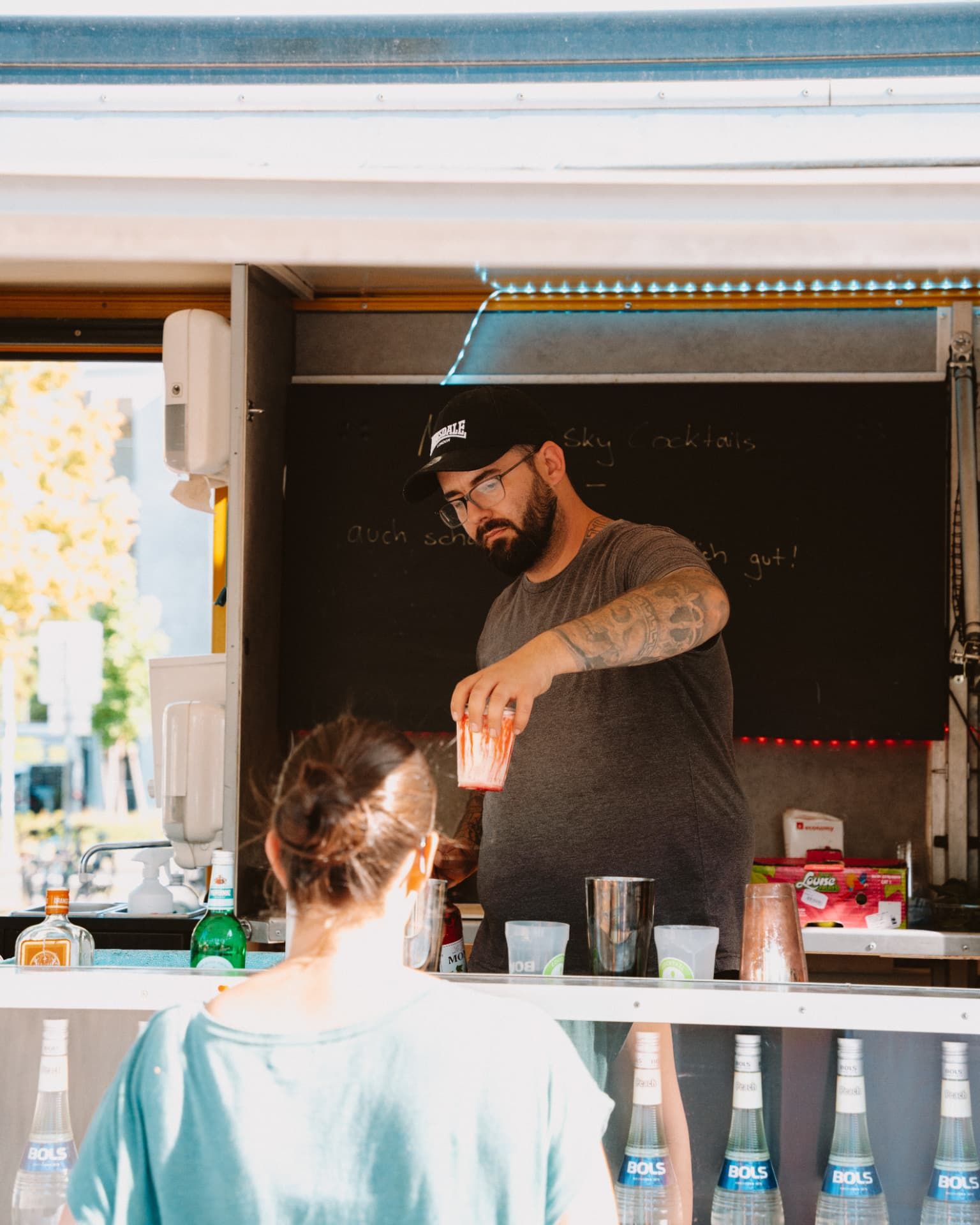 Barkeeper reicht einen fertigen Cocktail über den Tresen des Cocktailtrucks