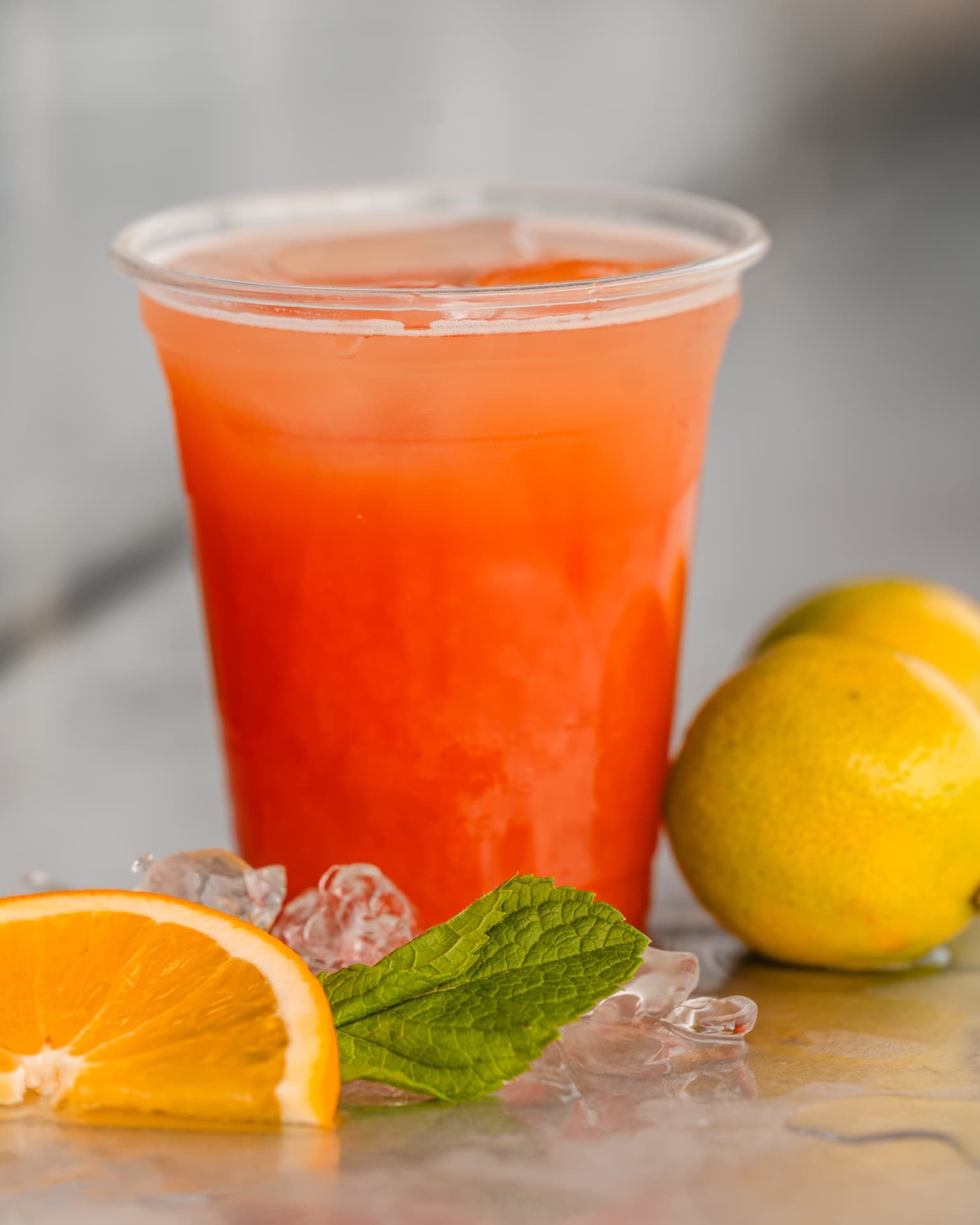 Orangefarbener Cocktail im Becher mit Orangenscheibe und Minze
